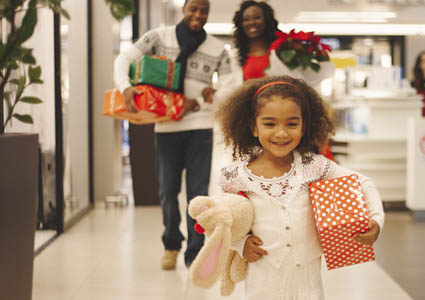 young family walking through store holding holiday presents